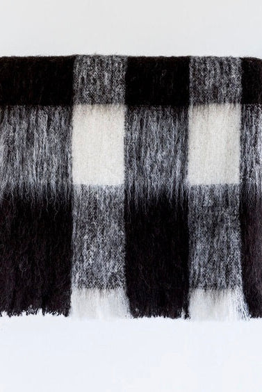 Alpaca fleece throw in Friesian colour folded on rack.