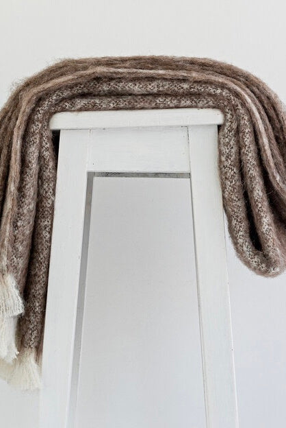 Alpaca fleece throw in Pumice colour draped on chair.