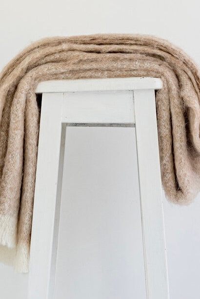 Alpaca fleece throw in sand colour draped on chair.