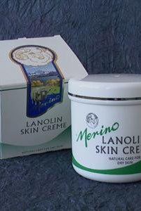 Merino 100g Lanolin Skin Crème with branding on a blanket next to its packaging box.