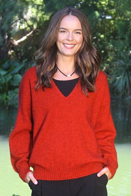 Woman wearing the Lothlorian - Merino & Possum Cavern V Neck Jumper (9789) in the colour Pumpkin.