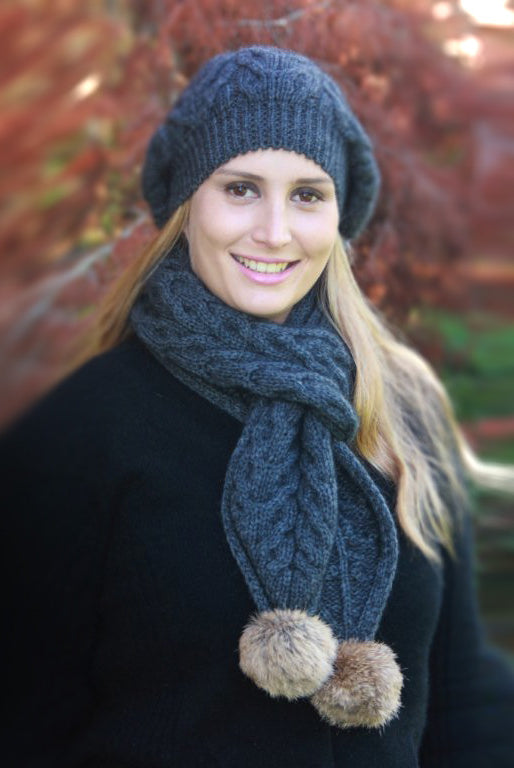 Woman wearing dark blue scarf and beanie with pom poms