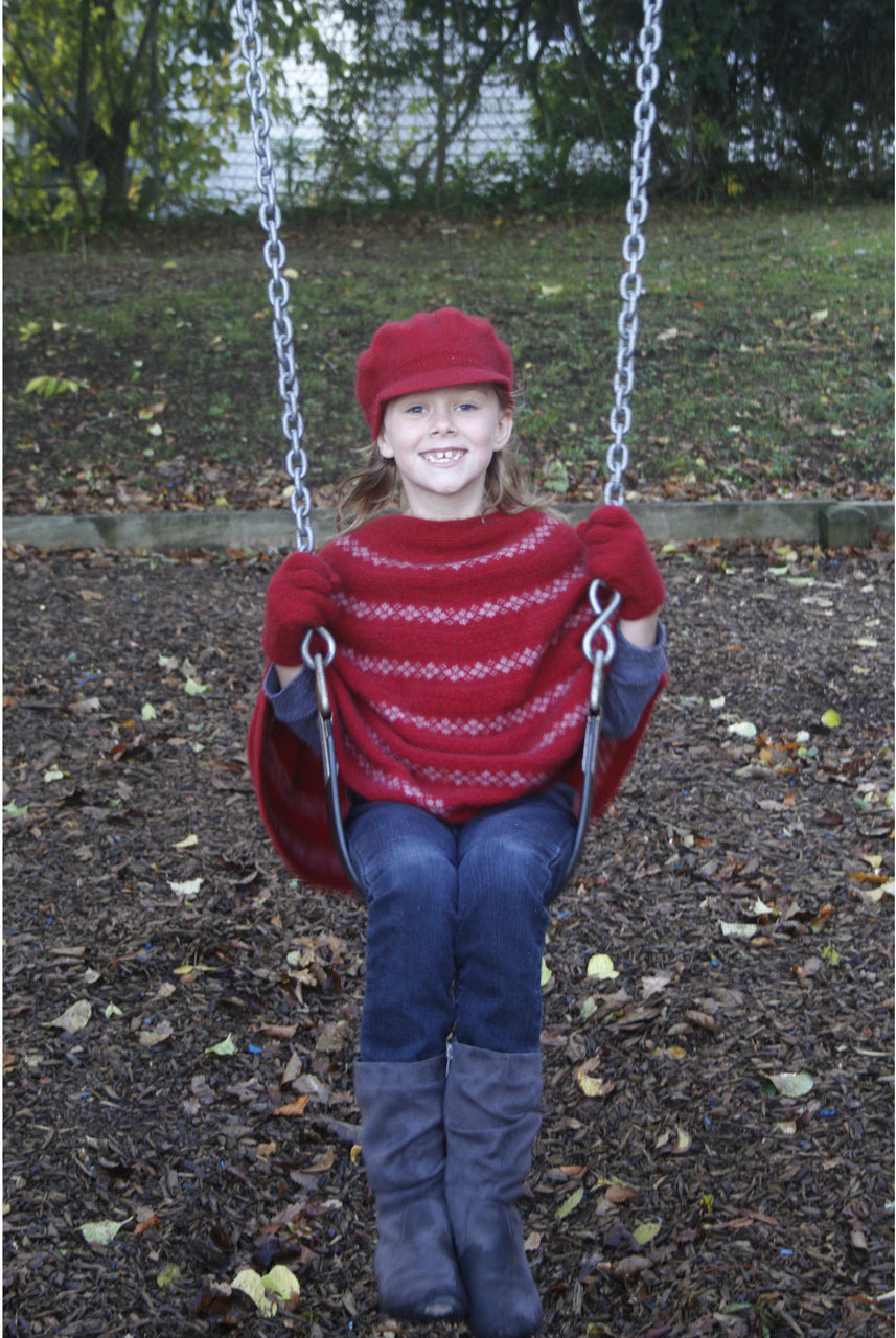 Girl sitting on swing wearing red Gatsby hat.