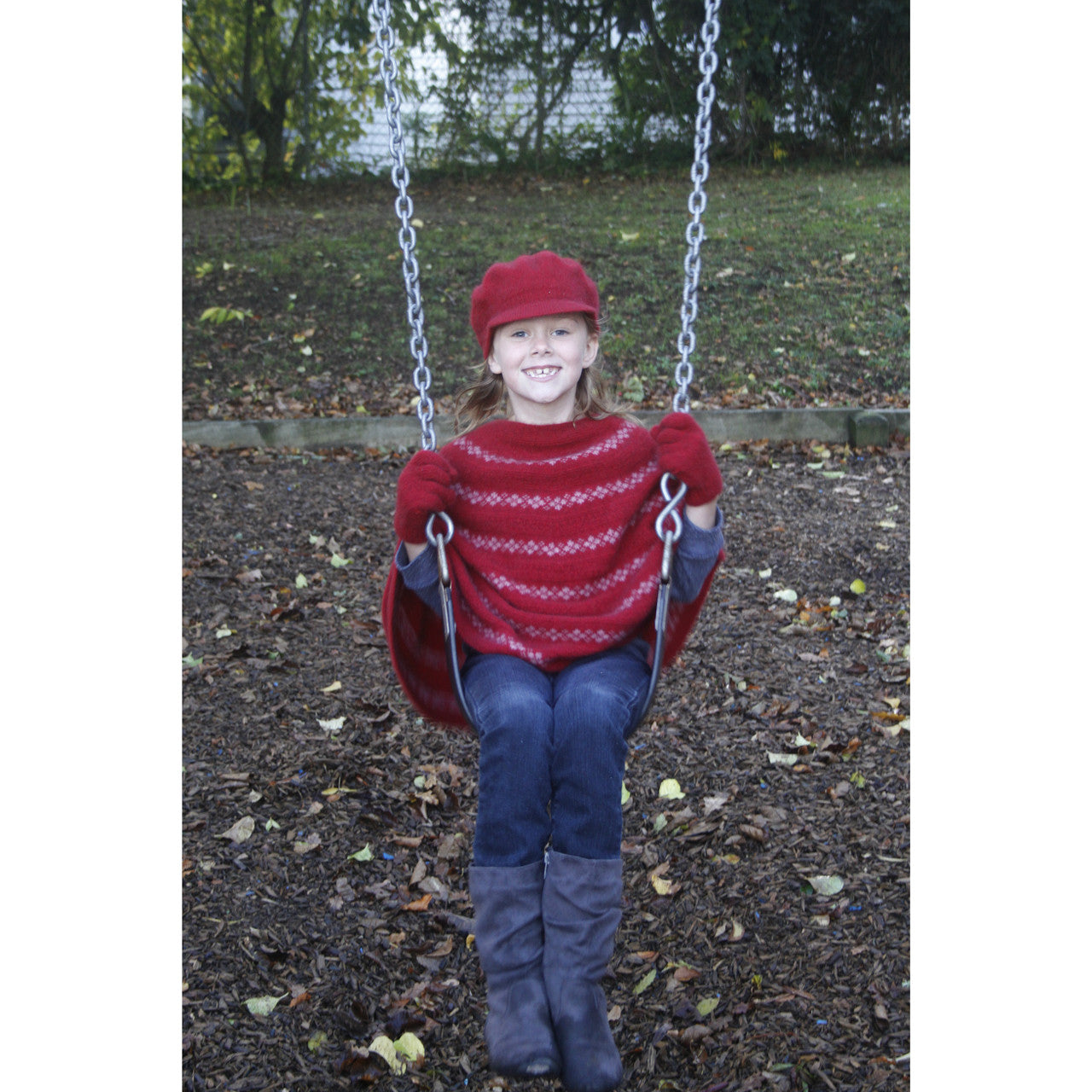 Girl sitting on swing wearing red Gatsby hat.
