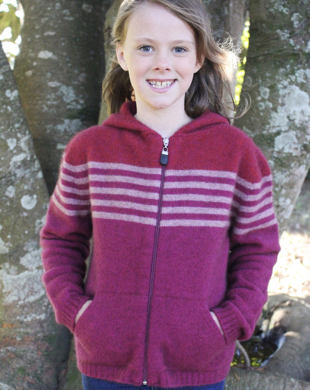 Girl standing wearing fuchsia colour striped hoodie.