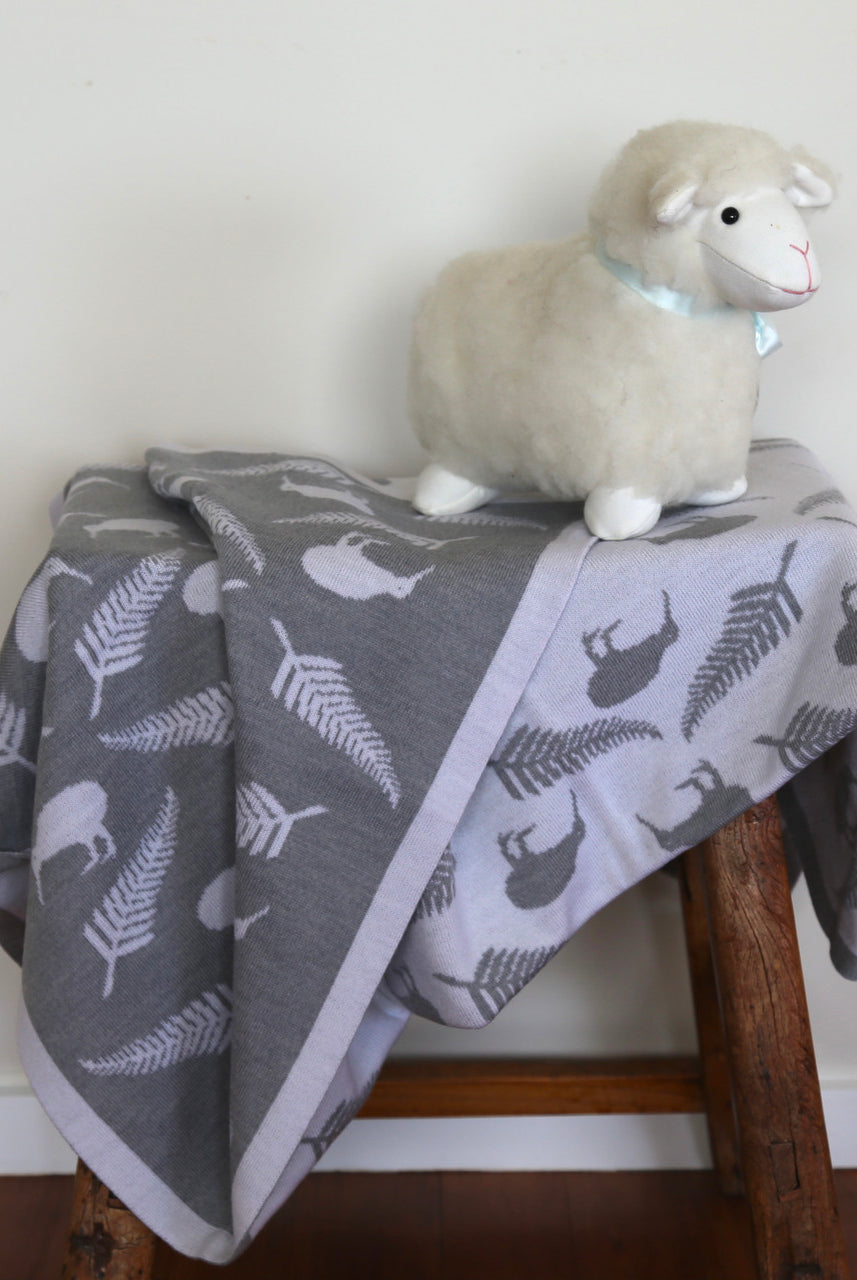 Baby cot blanket in colour silver and off white, on chair.