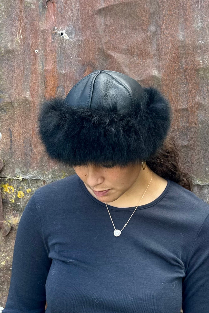 Woman standing wearing a Black coloured Four Peaks Classic Panelled Lambskin & Possum Fur Hat.