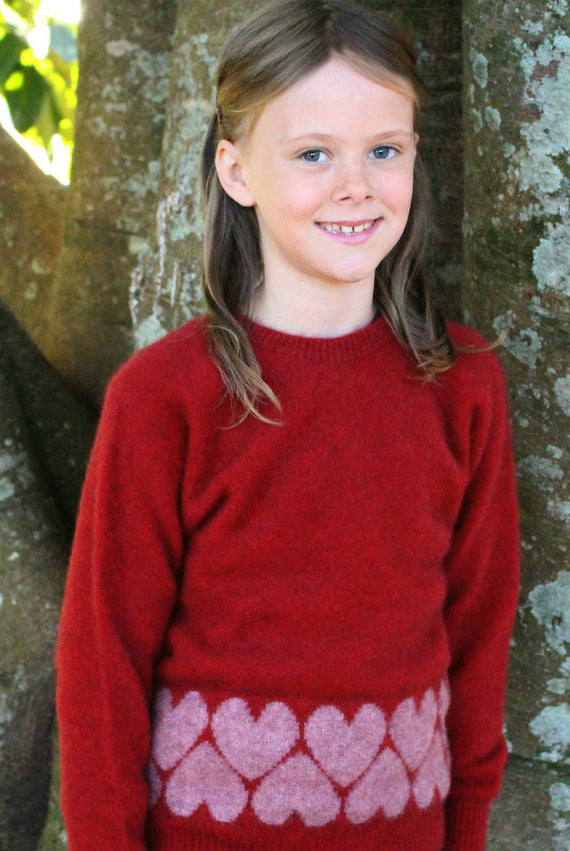Girl standing wearing Jumper in colour red.