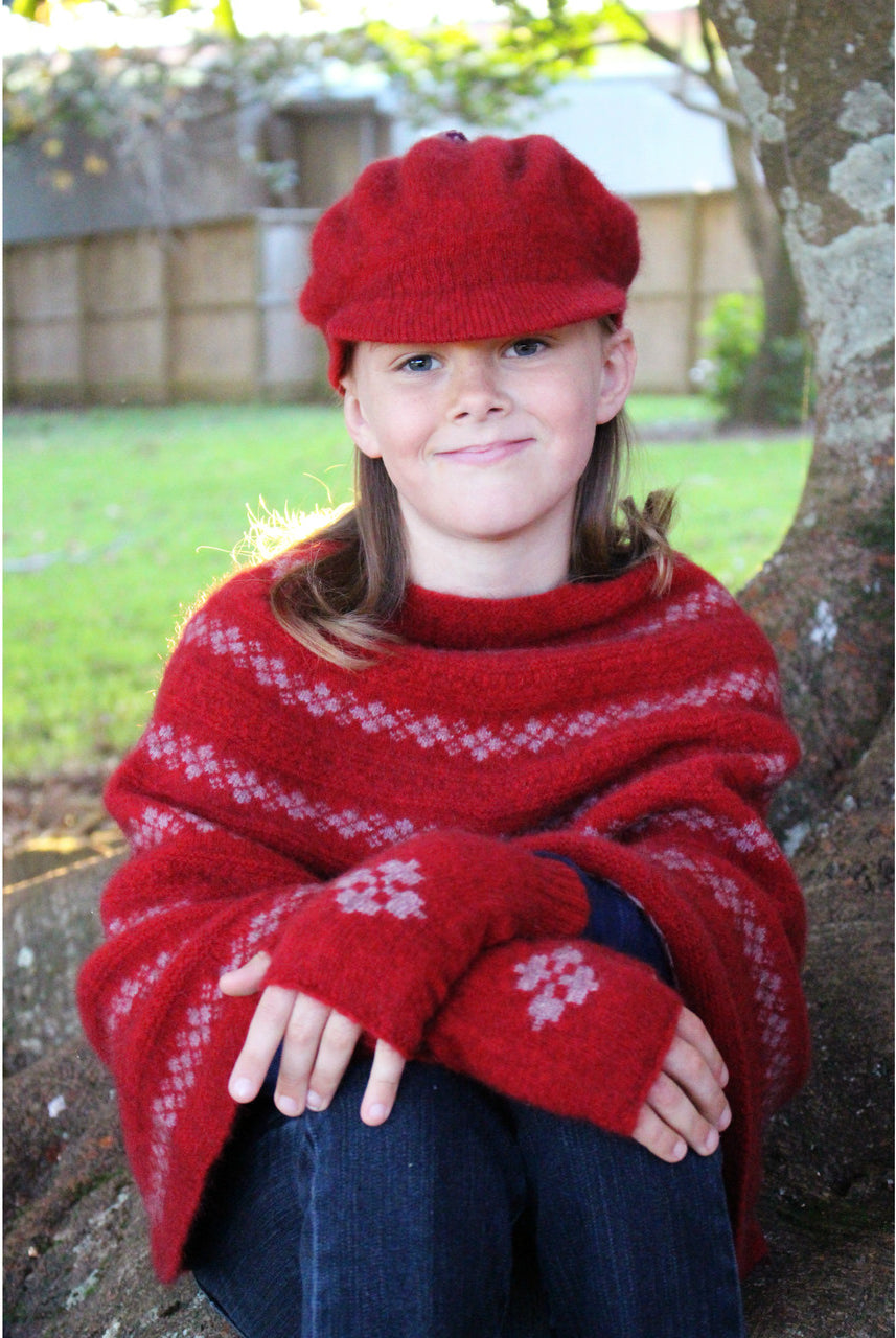 Girl sitting wearing Poncho in colour red.