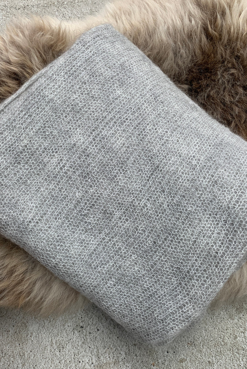 Folded silver-coloured Knight Mohair Throw on fur rug.
