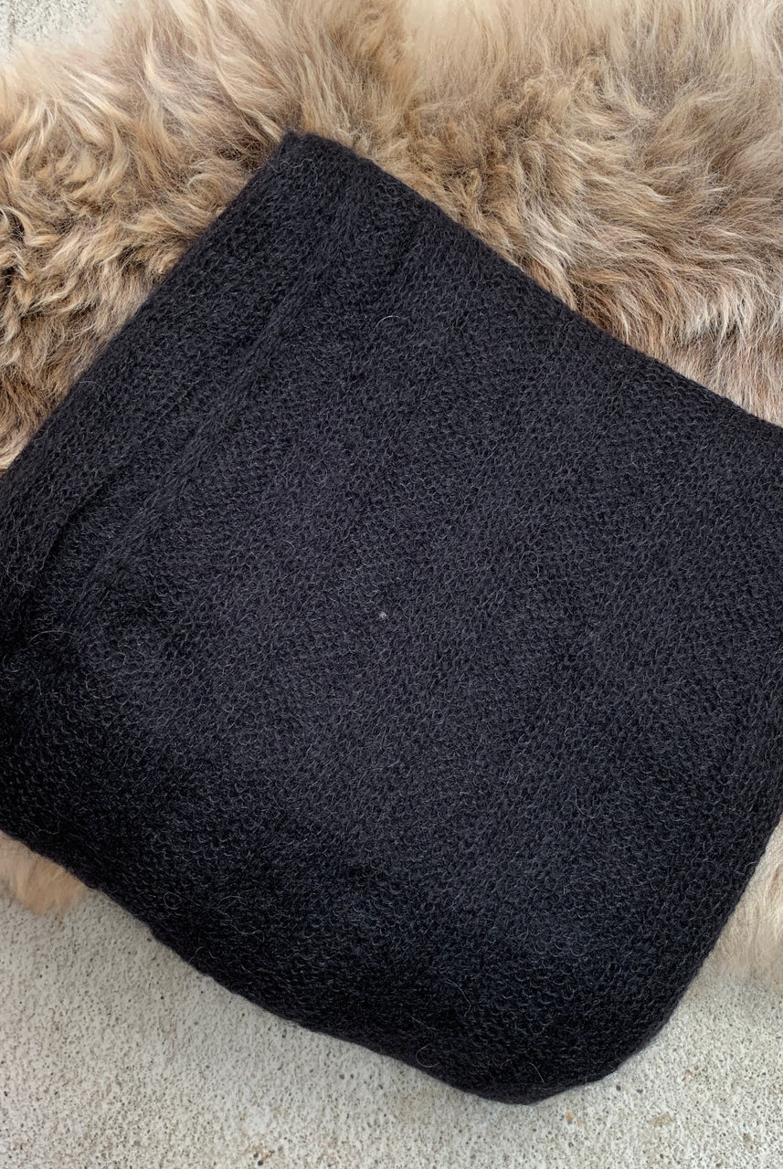 Folded black-coloured Knight Mohair Throw on fur rug.