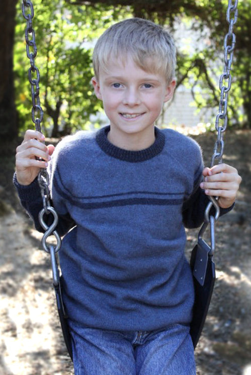 Boy on swing wearing Denim colour jumper.