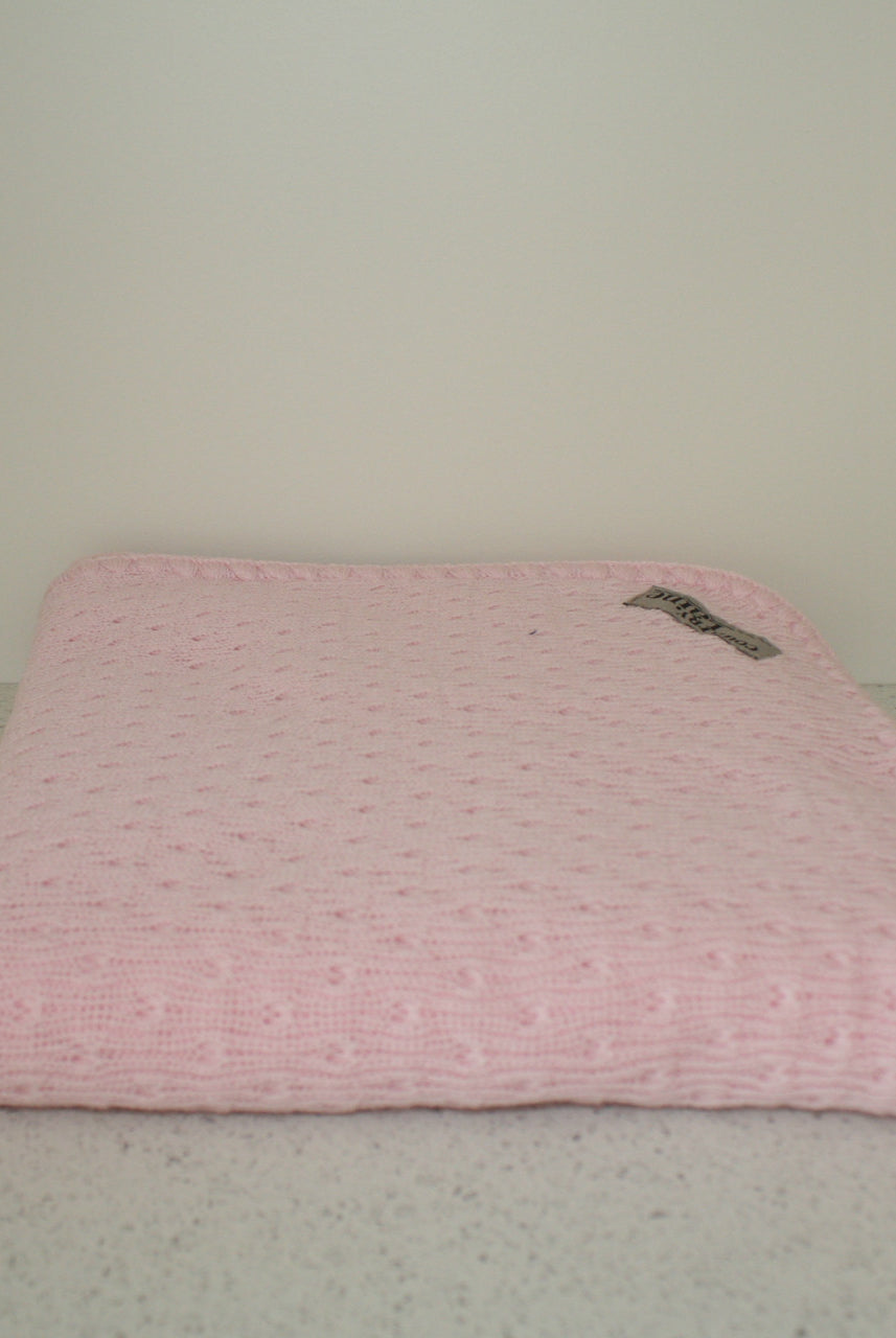 Pink coloured baby eyelet blanket.