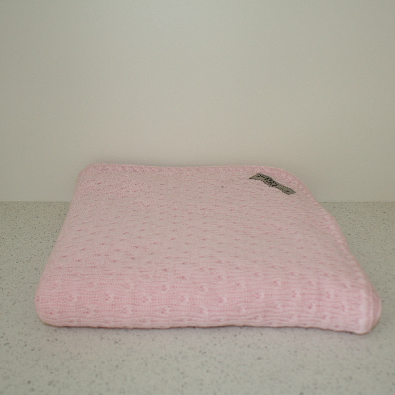 Pink coloured baby eyelet blanket.