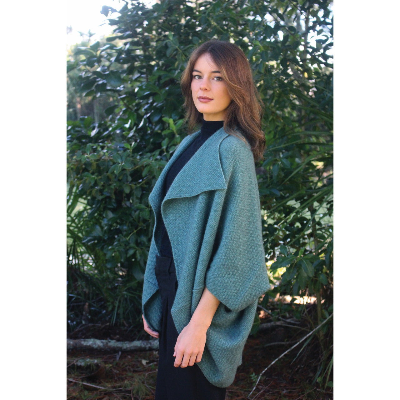 Woman wearing Takahe cape in colour Sage
