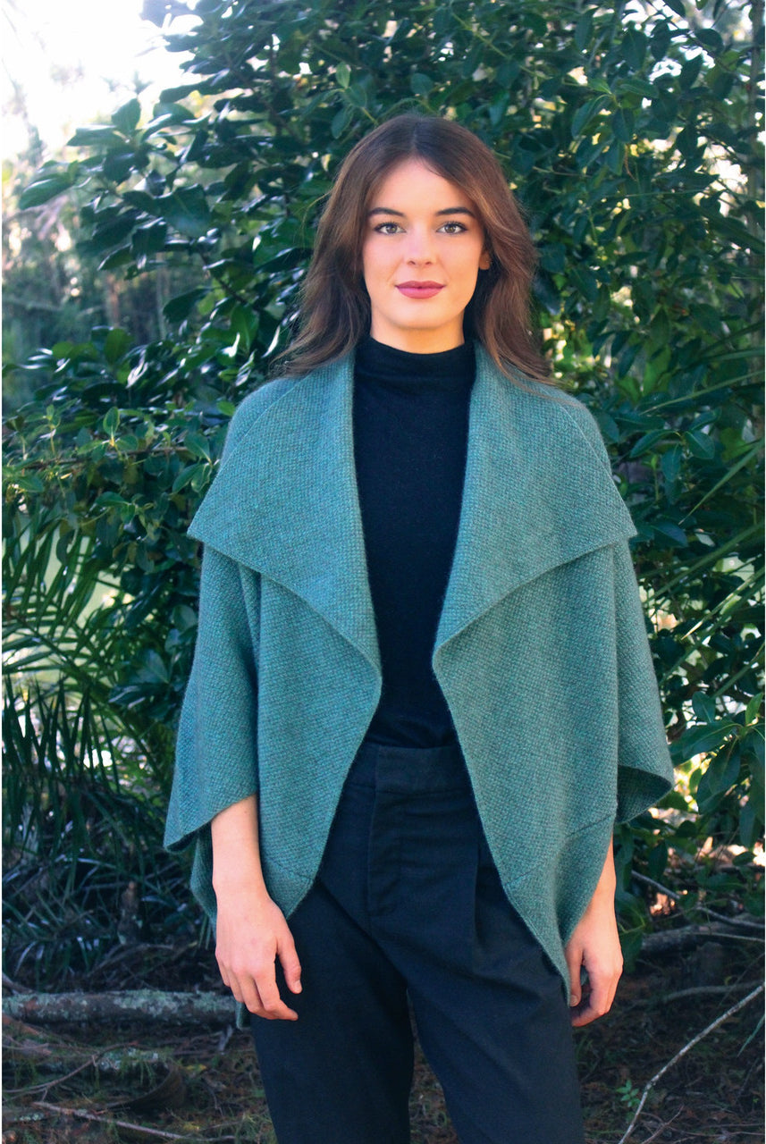 Woman wearing Takahe cape in colour Sage
