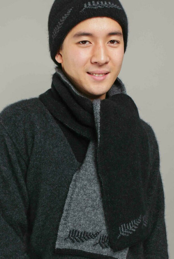Man wearing a black coloured Koru Silver Fern Accessory Set of scarf, gloves, and beanie.