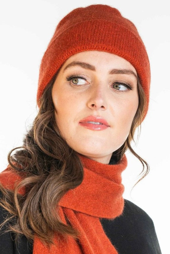 A woman wearing an sienna-coloured Koru Merino and Possum Plain Beanie.