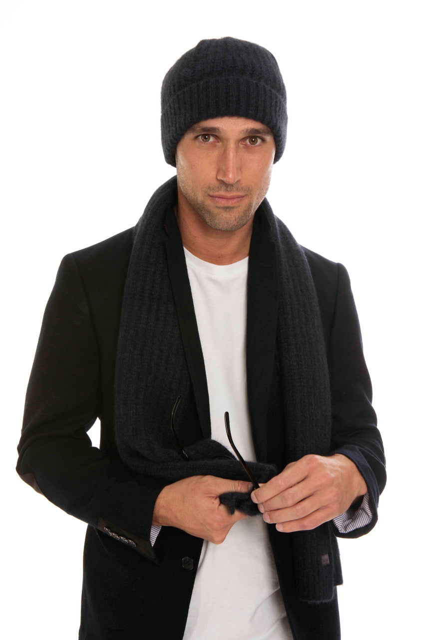 A man standing wearing an indigo-coloured Koru Merino and Possum Ribbed Scarf and Beanie Set.