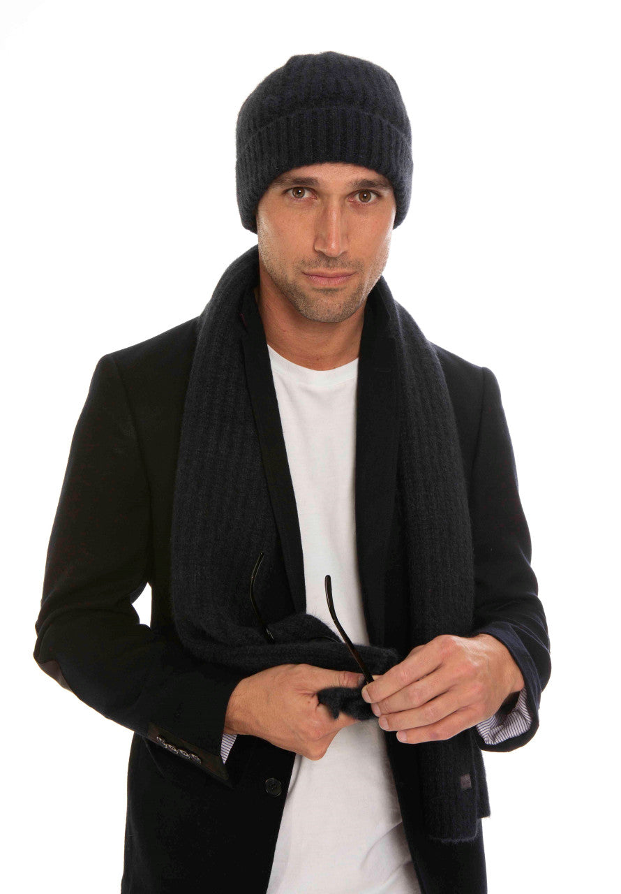 A man standing wearing an indigo-coloured Koru Merino and Possum Ribbed Scarf and Beanie Set.
