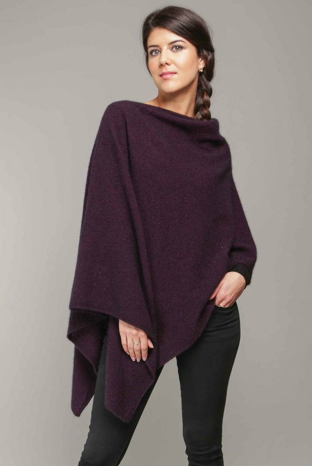 A woman standing wearing a grape-coloured Koru merino and possum Two Way Poncho.