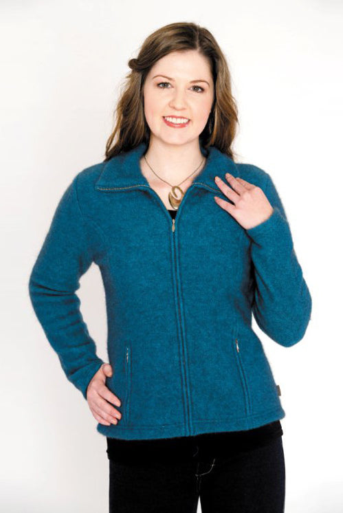 A woman standing wearing a pacific-coloured Koru merino and possum Shaped Zip Jacket.