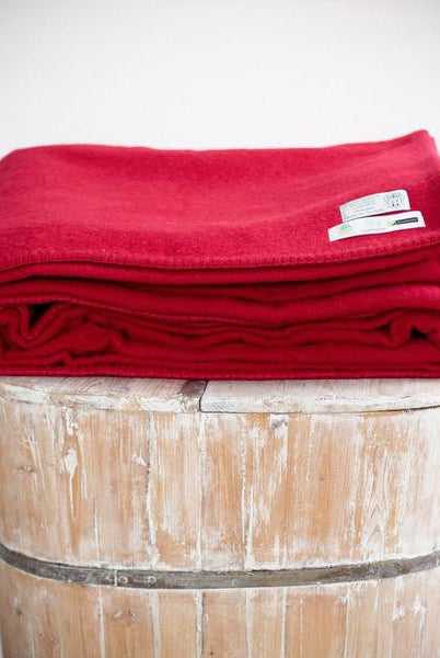 Folded cherry colour king wool blanket with co-ordinated stitch.