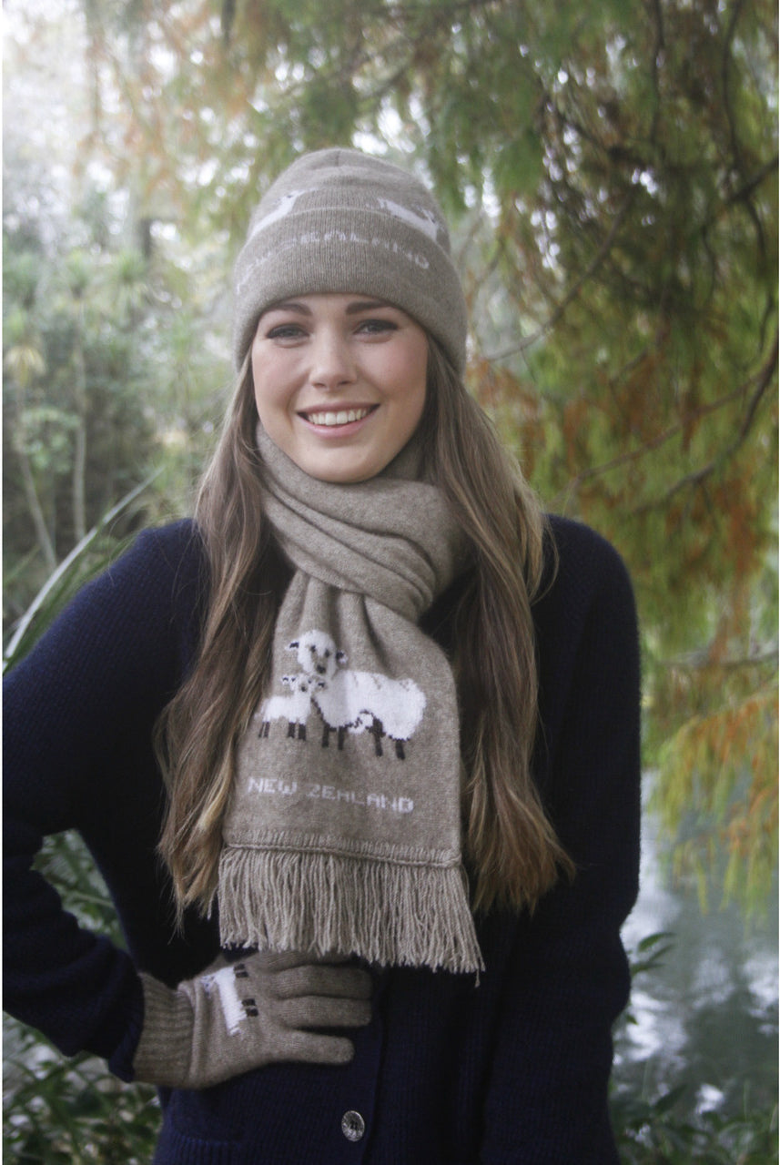 Woman standing outside wearing sheep detailed scarf, beanie and gloves