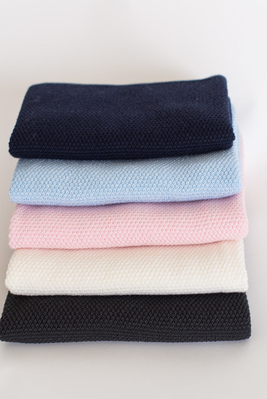 Stack of different coloured baby blankets.