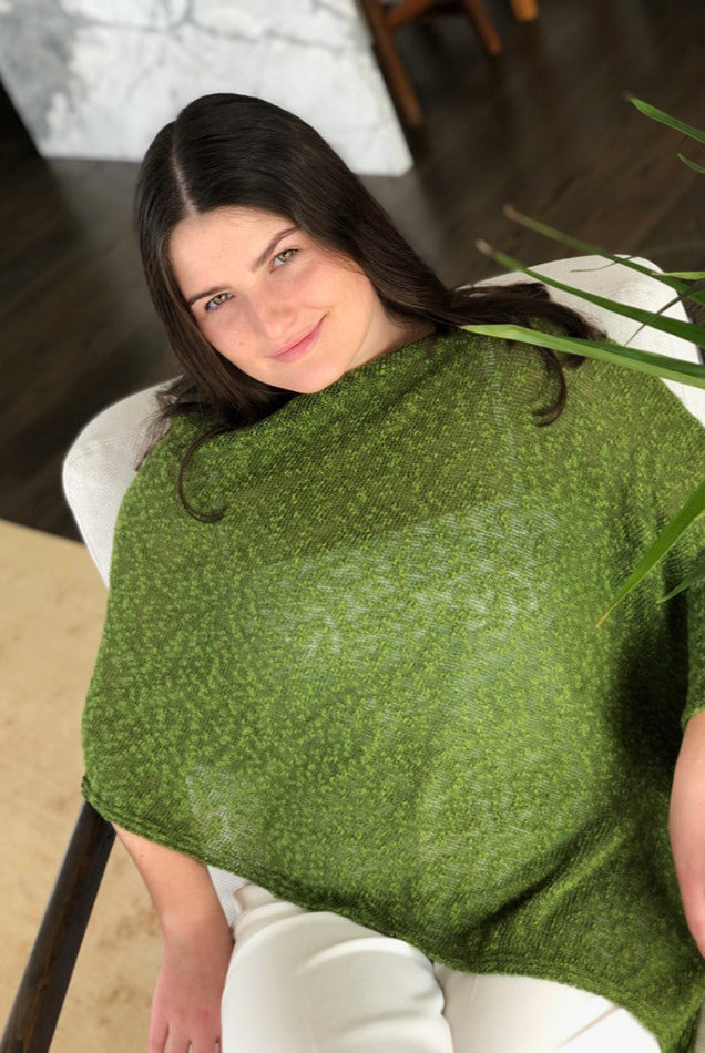 Woman sitting down wearing cotton poncho. Colour Fern
