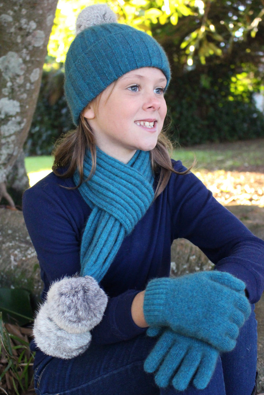 Girl wearing teal colour scarf, beanie and glove set.