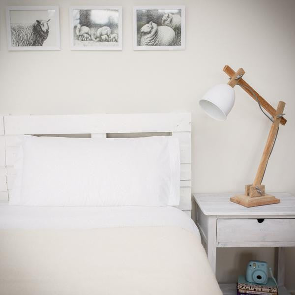 White wool blanket with darker stitching on bed.