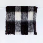 Alpaca fleece throw in Friesian colour folded on rack.