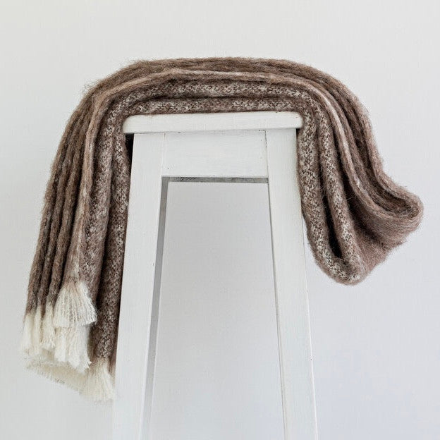 Alpaca fleece throw in Pumice colour draped on chair.