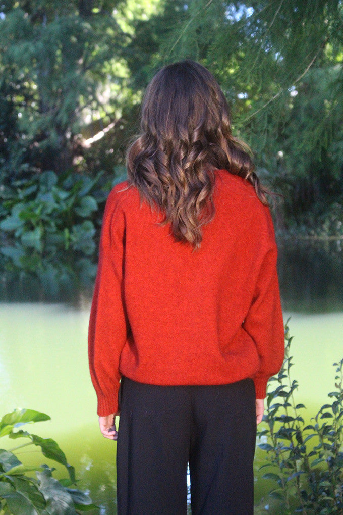 Woman wearing the Lothlorian - Merino & Possum Cavern V Neck Jumper (9789) in the colour Pumpkin.
