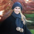 Woman wearing dark blue scarf and beanie with pom poms