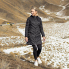 Woman wearing Moke - Arnie Reversible Packable Down Coat (ARNIE) in colour Black/Rose Violet on hill with snow in backgroumd.