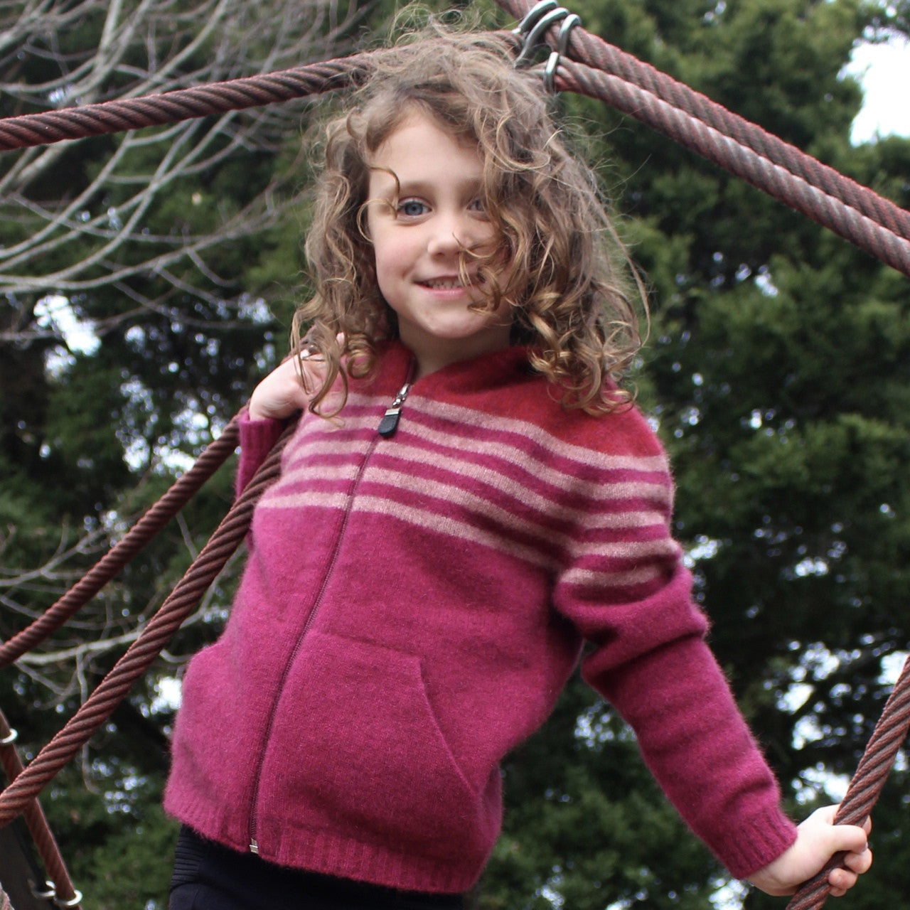 Girl leaning sideways wearing fuchsia colour striped hoodie.