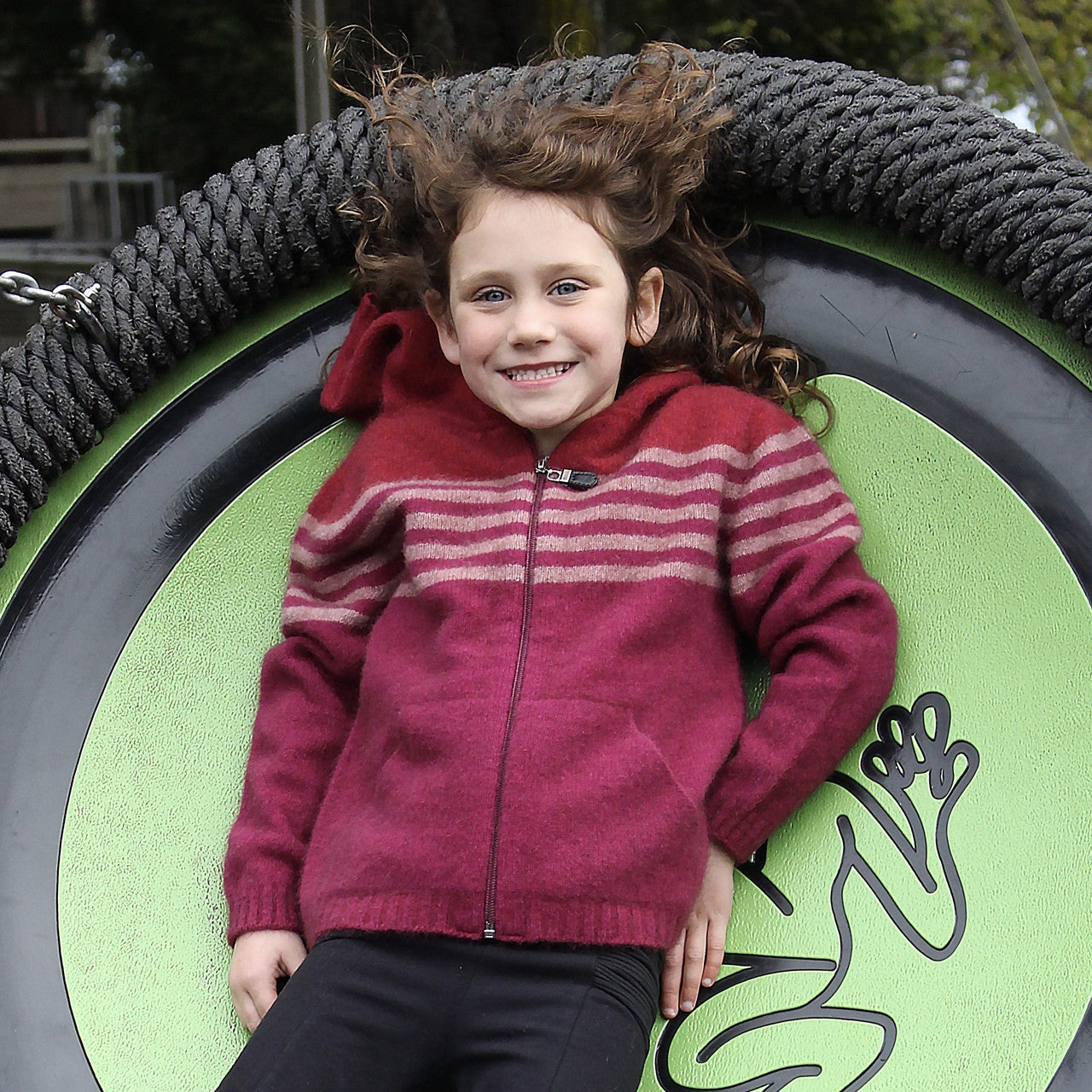 Girl leaning back wearing fuchsia colour striped hoodie.