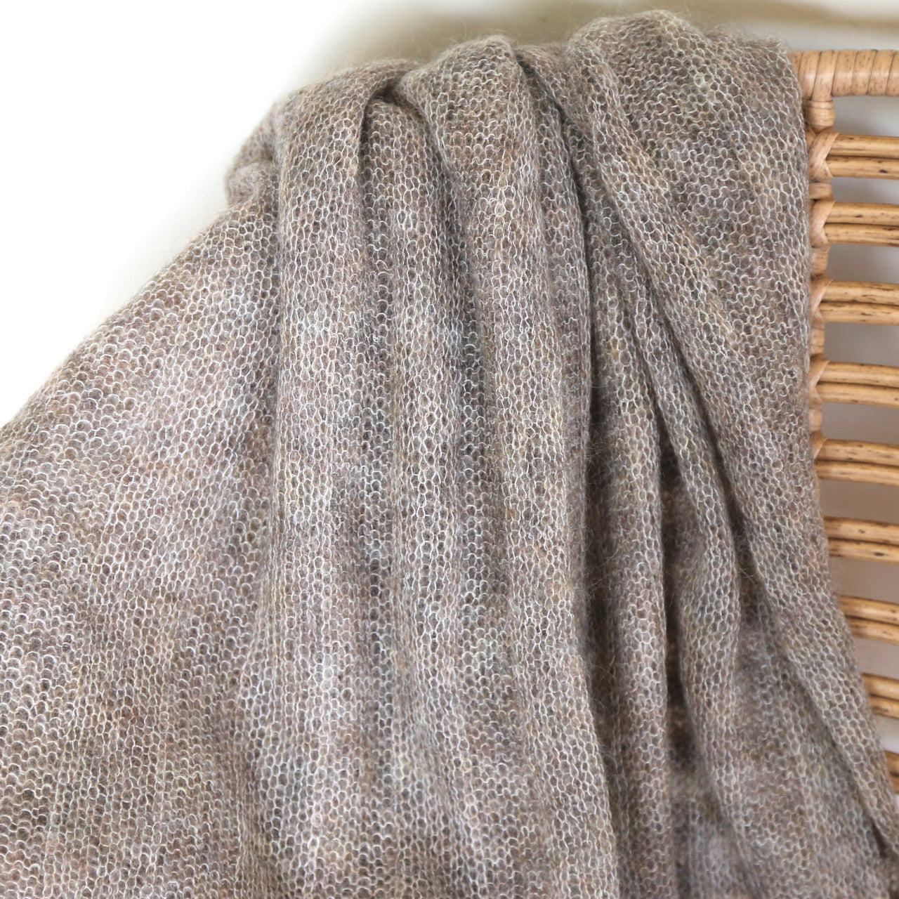 Close up of fawn-coloured Knight Mohair Throw draped over chair.