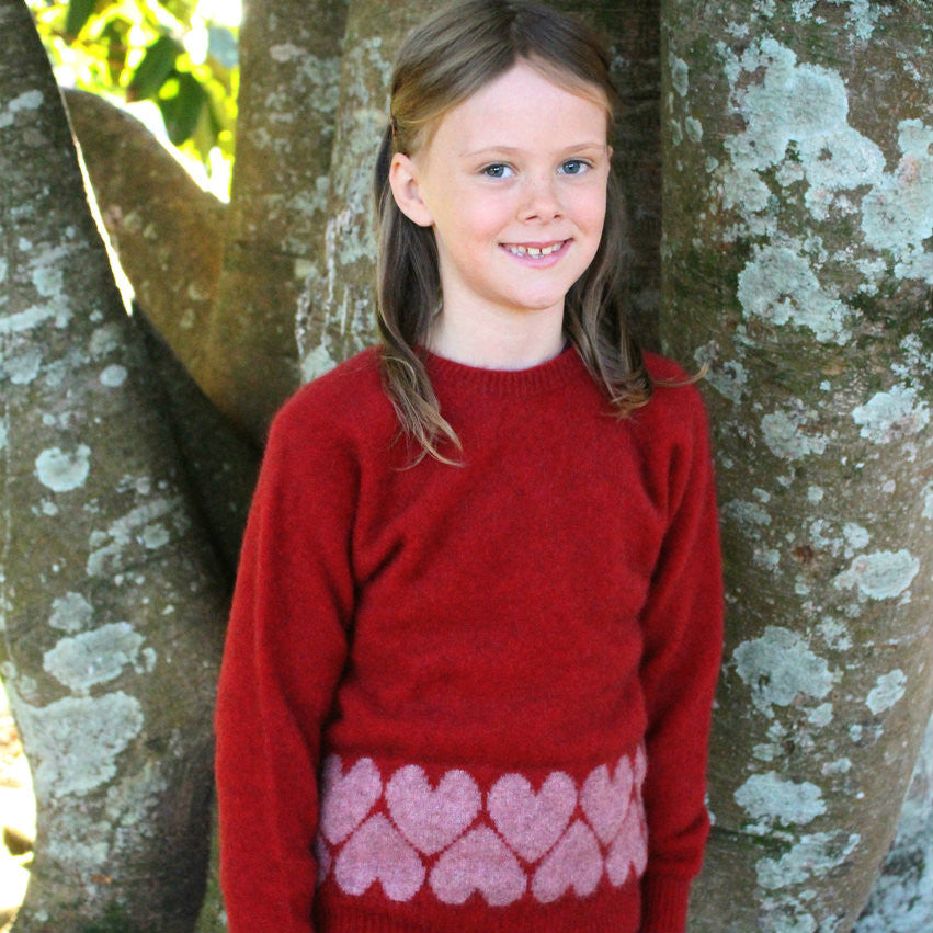 Girl standing wearing Jumper in colour red.