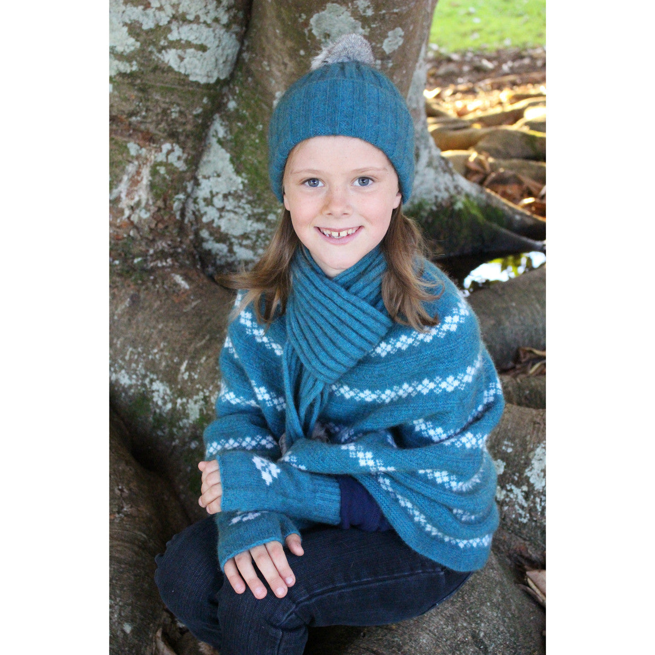 Girl sitting wearing Poncho in colour teal.