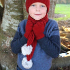 Boy wearing red colour scarf, beanie and glove set.