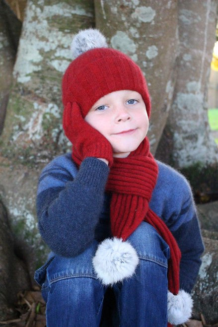 Child with hand on face wearing beanie. Colour Red