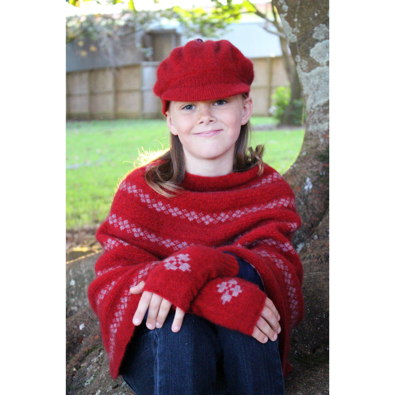 Girl sitting wearing Poncho in colour red.