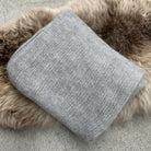 Folded silver-coloured Knight Mohair Throw on fur rug.