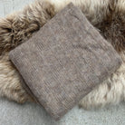 Folded fawn-coloured Knight Mohair Throw on fur rug.