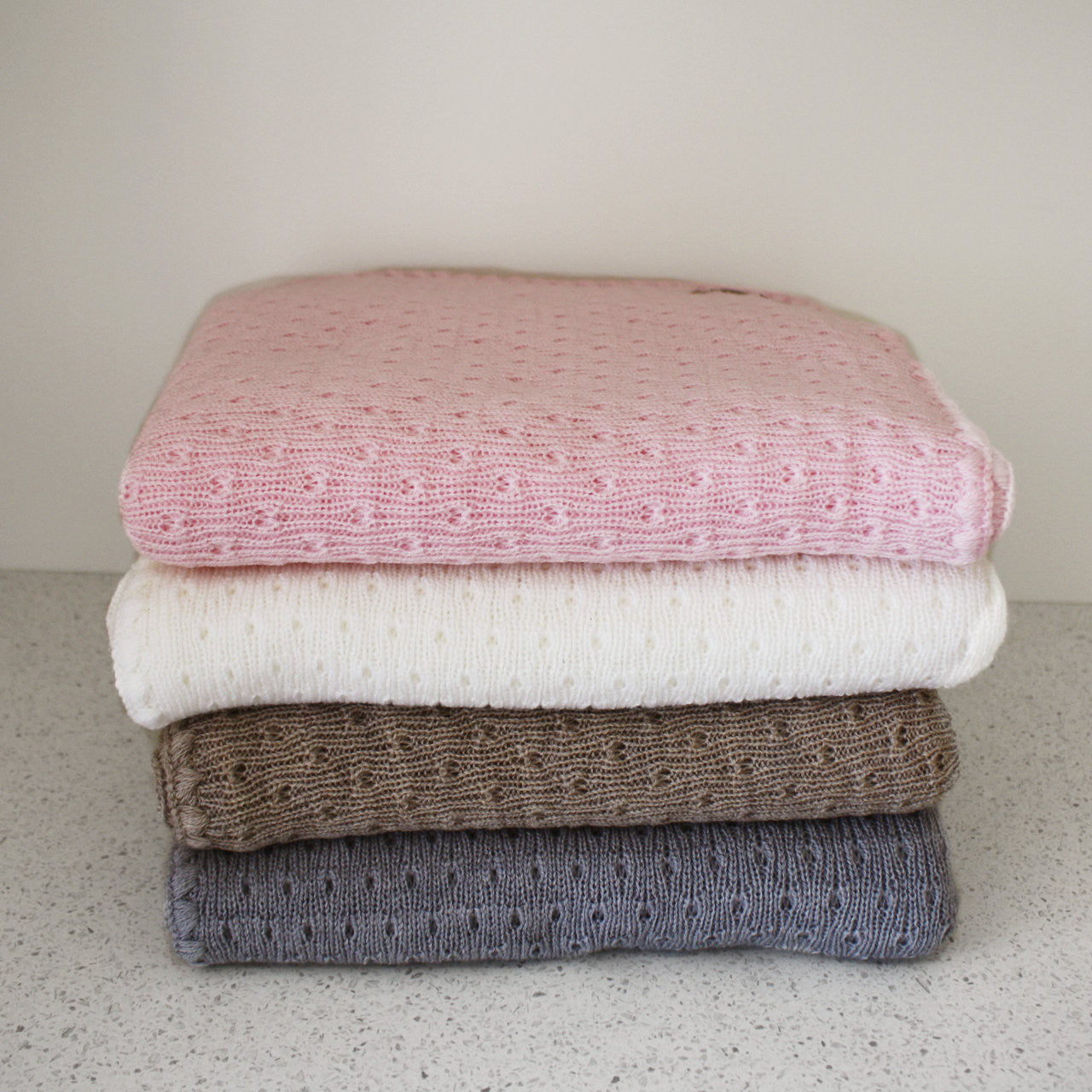Stack of different coloured baby blankets.