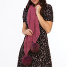 Woman wearing a rose and wildberry coloured Koru merino and possum fur Pom Pom Scarf.