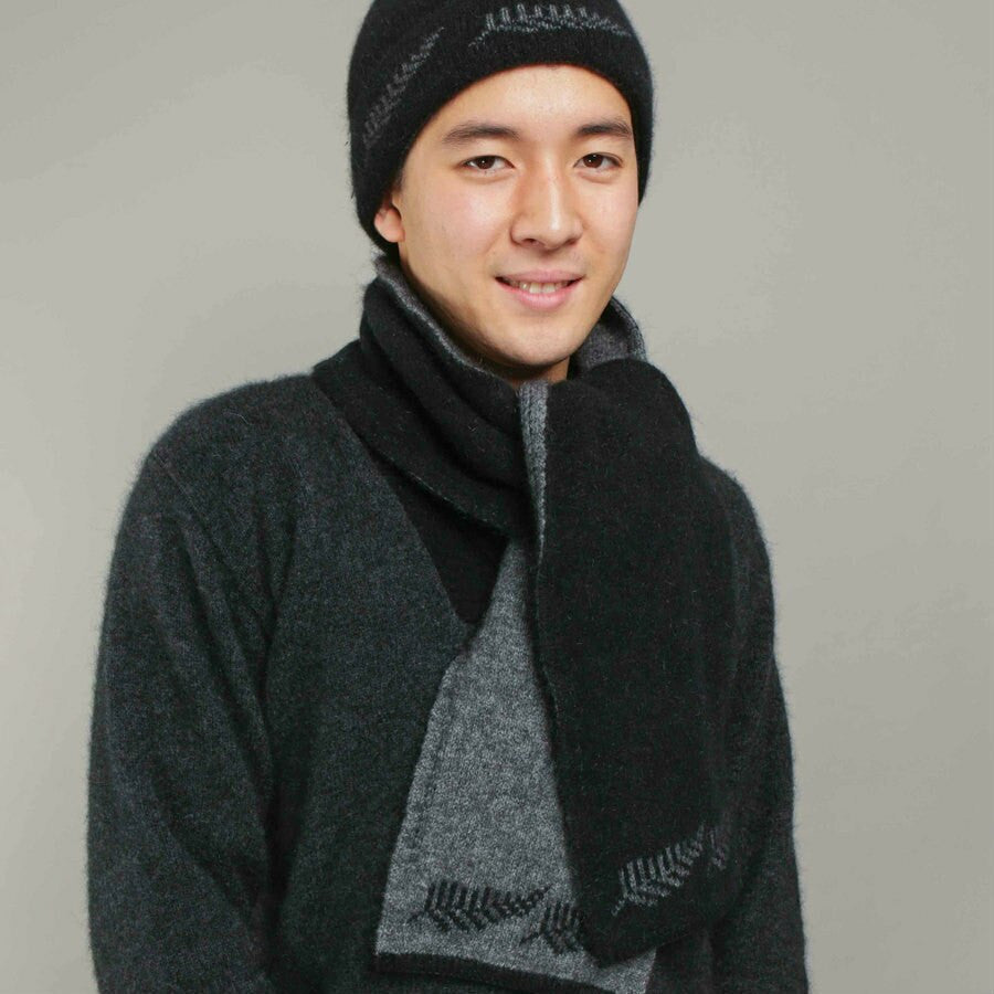 Man wearing a black coloured Koru Silver Fern Accessory Set of scarf, gloves, and beanie.